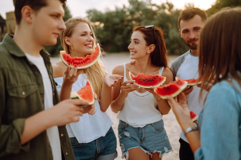 groepje jonge mensen die watermeloen eten
